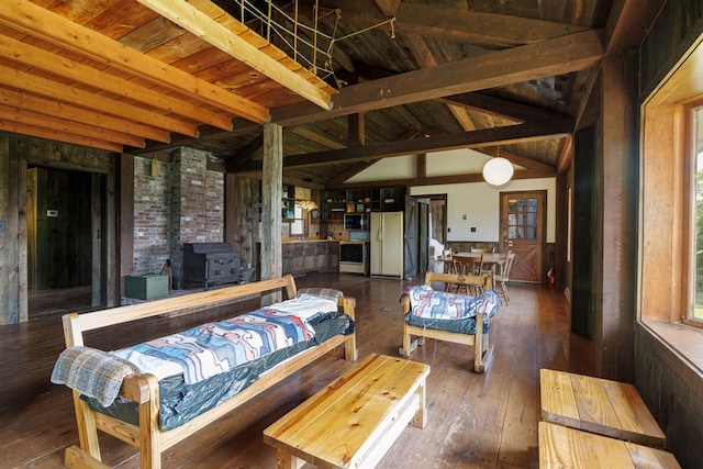 interior space featuring a wealth of natural light, vaulted ceiling with beams, a wood stove, and dark hardwood / wood-style flooring