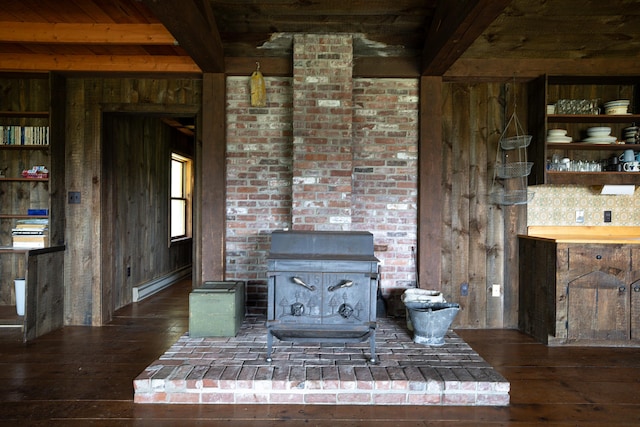 unfurnished living room featuring beam ceiling, a wood stove, dark hardwood / wood-style flooring, and wooden walls