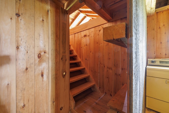 staircase featuring washer / dryer, wood walls, hardwood / wood-style flooring, and beamed ceiling