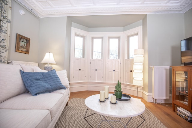 living room featuring light hardwood / wood-style flooring, crown molding, and radiator heating unit