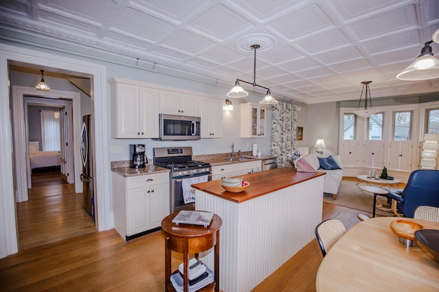 kitchen with light stone countertops, appliances with stainless steel finishes, sink, light hardwood / wood-style floors, and white cabinets