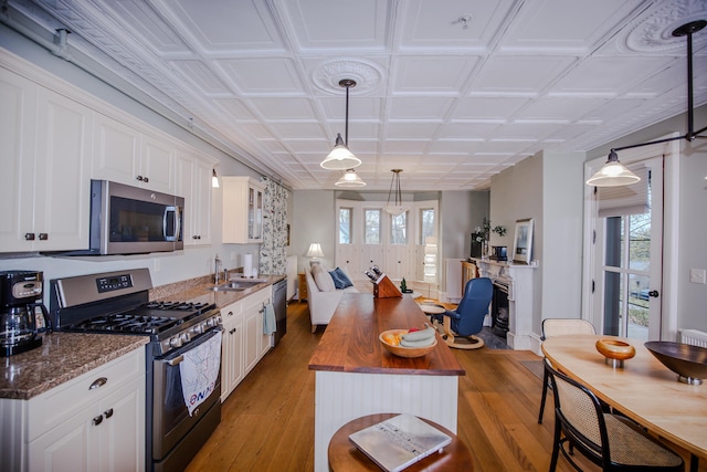 kitchen featuring appliances with stainless steel finishes, light hardwood / wood-style flooring, white cabinets, and plenty of natural light