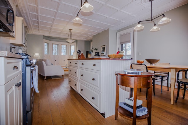 kitchen with white cabinets, stainless steel appliances, wood-type flooring, and pendant lighting