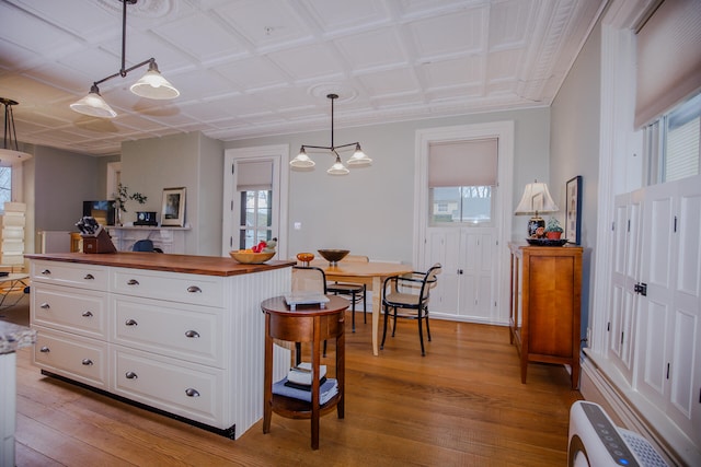 kitchen with white cabinetry, light wood-type flooring, plenty of natural light, and hanging light fixtures