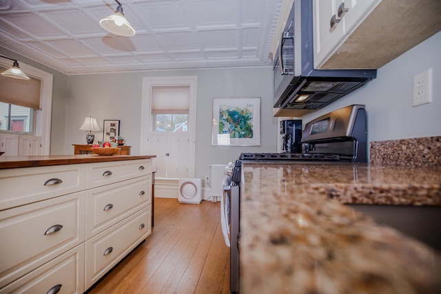 kitchen featuring light hardwood / wood-style flooring, white cabinetry, and stainless steel gas range