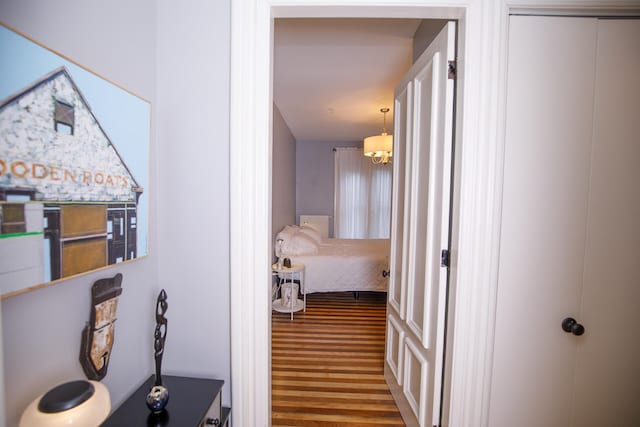 hallway with a notable chandelier and wood-type flooring