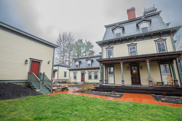 back of property featuring a yard and covered porch