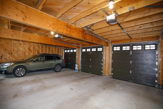 garage featuring a garage door opener and wooden walls