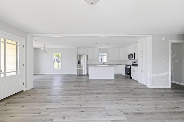 kitchen featuring open floor plan, appliances with stainless steel finishes, a chandelier, and a healthy amount of sunlight