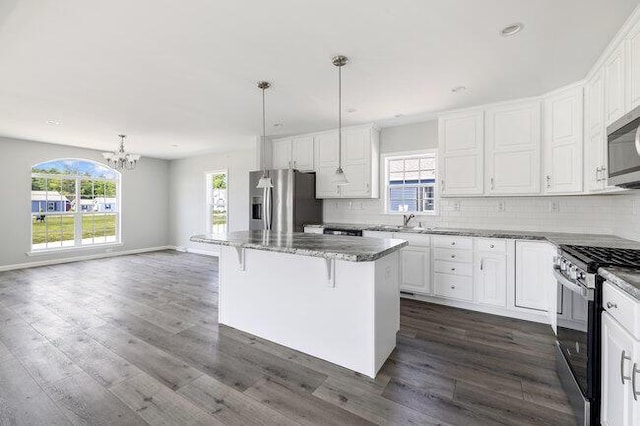 kitchen featuring backsplash, a center island, appliances with stainless steel finishes, and plenty of natural light