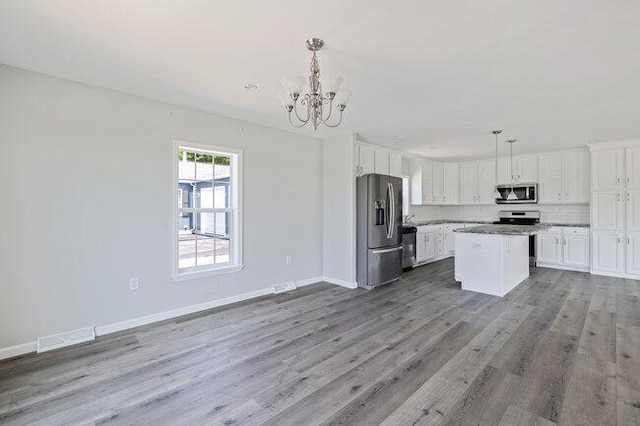 kitchen featuring stainless steel appliances, a notable chandelier, white cabinetry, and wood finished floors