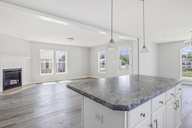 kitchen featuring light wood-type flooring, a fireplace, open floor plan, a kitchen island, and white cabinets