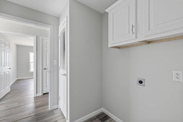laundry area featuring hookup for an electric dryer, light wood-style flooring, baseboards, and cabinet space