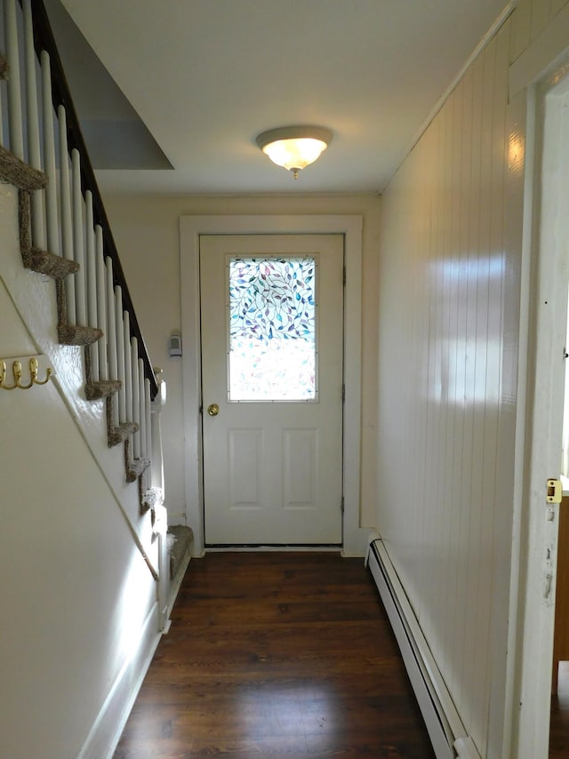 doorway to outside featuring a baseboard radiator, dark wood-type flooring, and wooden walls