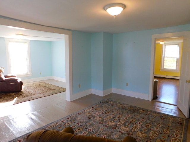 unfurnished room featuring hardwood / wood-style floors and a baseboard radiator