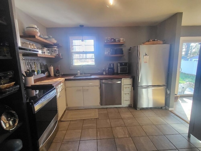 kitchen with open shelves, stainless steel appliances, dark countertops, white cabinetry, and a sink