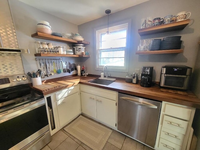 kitchen with butcher block counters, a sink, appliances with stainless steel finishes, wall chimney range hood, and open shelves