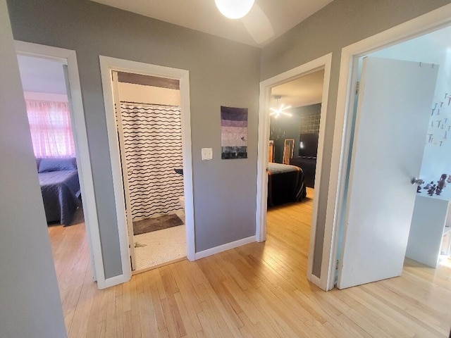 hall featuring light wood-style flooring and baseboards