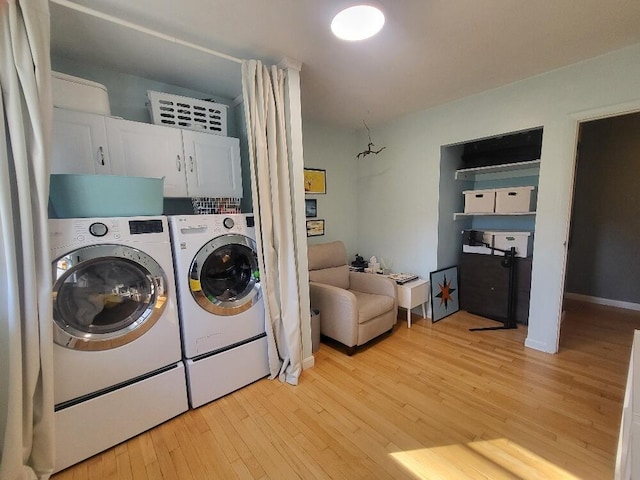 laundry area featuring cabinet space, light wood-style floors, and washing machine and clothes dryer