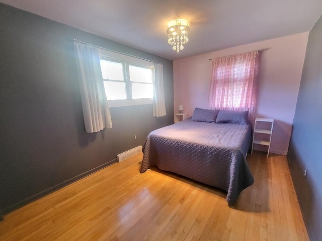 bedroom with baseboards, visible vents, a chandelier, and hardwood / wood-style floors