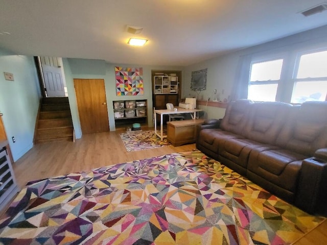 living room with wood finished floors, visible vents, and stairs