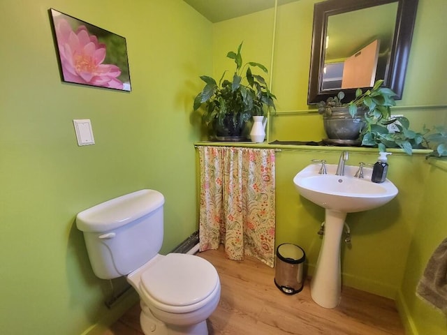 bathroom with baseboards, toilet, and wood finished floors