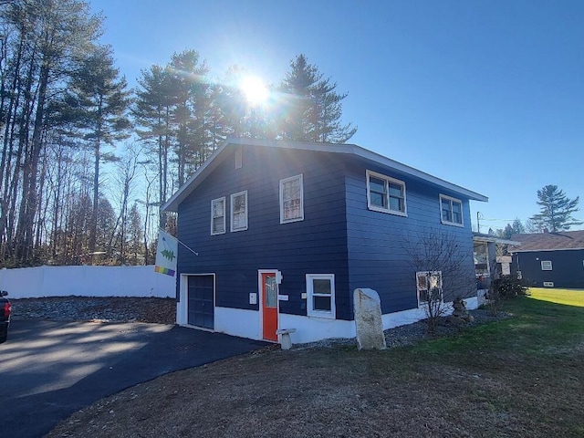 view of property exterior with a yard, aphalt driveway, and an attached garage