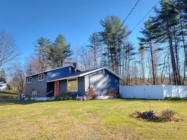 view of front facade with a chimney, fence, and a front lawn