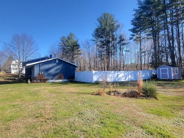 view of yard with an outbuilding, a storage unit, and fence