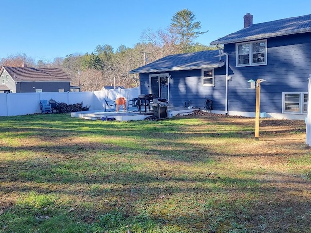 rear view of property with a yard, a chimney, and fence