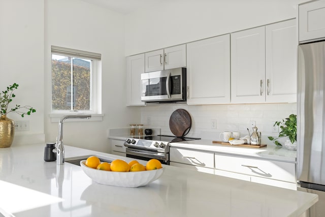 kitchen featuring tasteful backsplash, white cabinets, sink, and stainless steel appliances