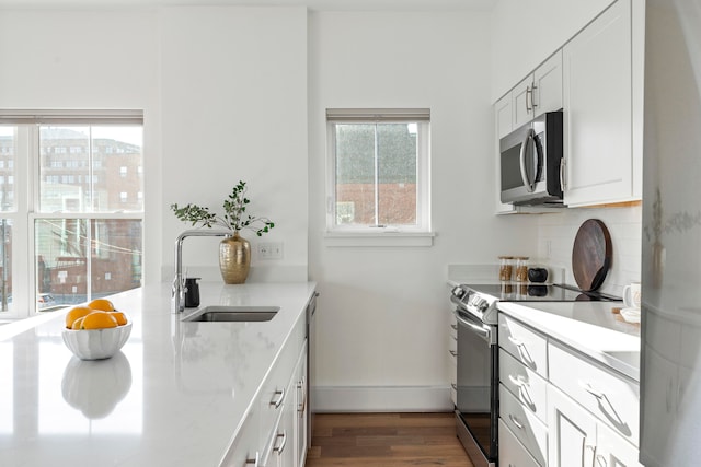 kitchen featuring dark wood-type flooring, decorative backsplash, sink, white cabinetry, and appliances with stainless steel finishes