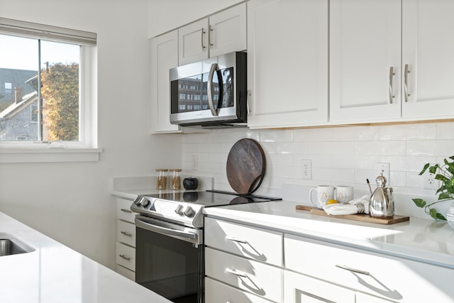 kitchen featuring appliances with stainless steel finishes, decorative backsplash, and white cabinets