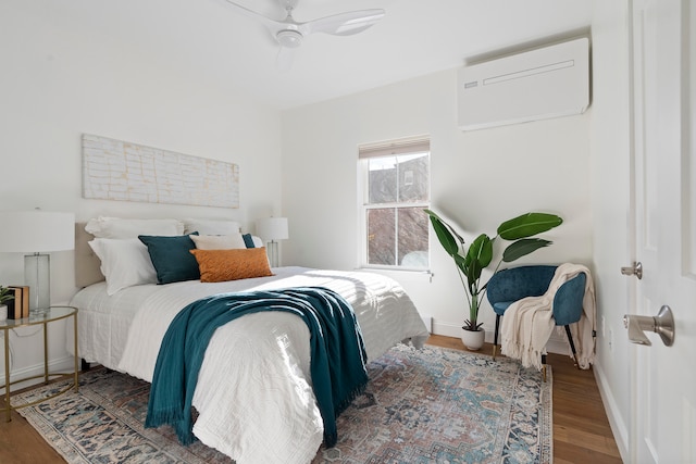 bedroom with hardwood / wood-style floors, ceiling fan, and an AC wall unit