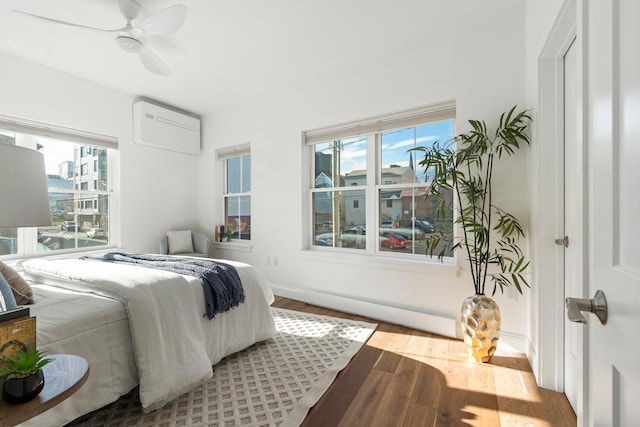 bedroom featuring ceiling fan, multiple windows, a wall mounted air conditioner, and wood-type flooring