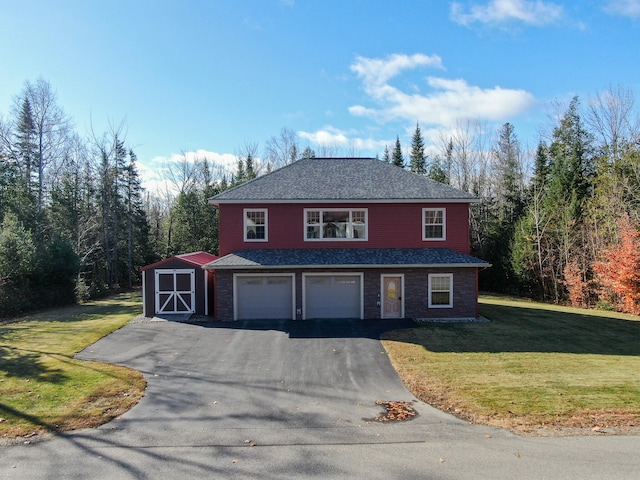 view of property featuring a garage, a front lawn, and a shed