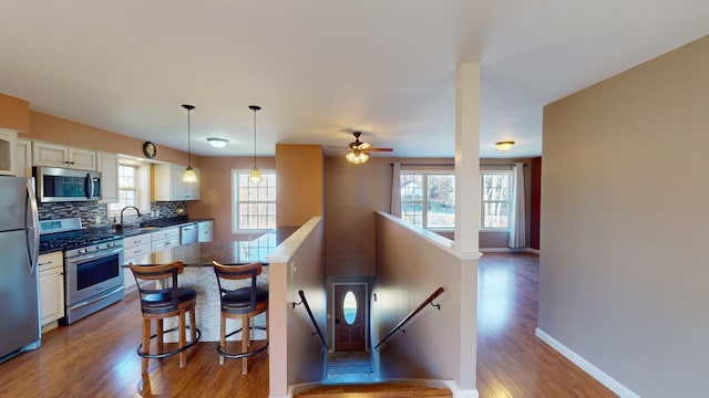 kitchen featuring white cabinets, a kitchen breakfast bar, stainless steel appliances, and wood-type flooring