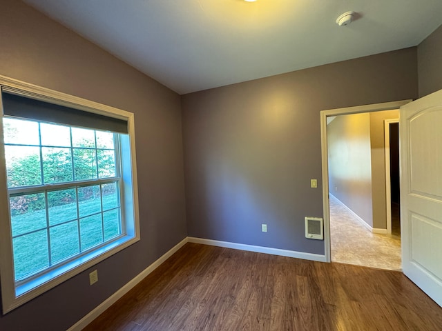 empty room with heating unit and hardwood / wood-style floors