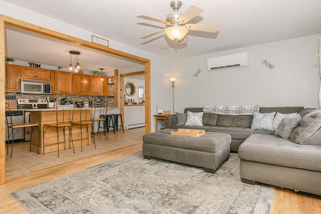 living room featuring baseboard heating, a wall unit AC, light hardwood / wood-style floors, and ceiling fan