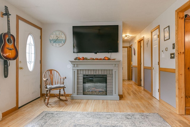 living room with a brick fireplace and light hardwood / wood-style flooring