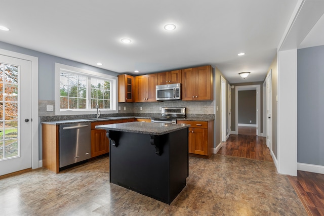 kitchen featuring a kitchen bar, a wealth of natural light, stainless steel appliances, and a center island