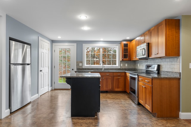 kitchen with stainless steel appliances, a kitchen breakfast bar, dark stone counters, a kitchen island, and decorative backsplash