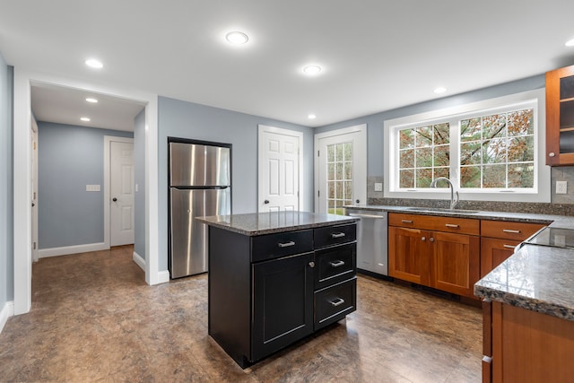 kitchen with stainless steel appliances, dark stone counters, sink, and a kitchen island