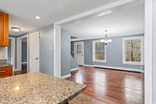 kitchen featuring light stone counters, baseboard heating, decorative light fixtures, a notable chandelier, and dark hardwood / wood-style flooring