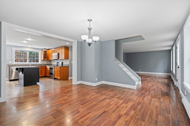 kitchen featuring stainless steel appliances, tasteful backsplash, a kitchen breakfast bar, hanging light fixtures, and dark hardwood / wood-style flooring