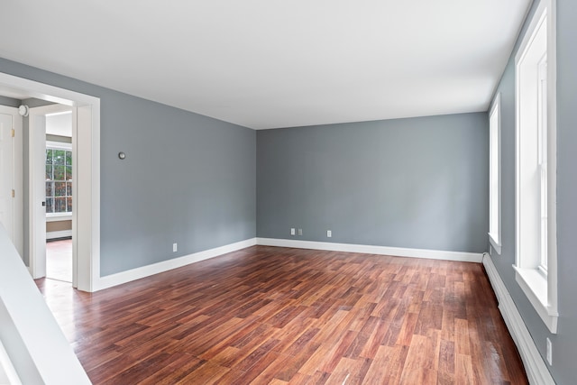 empty room featuring dark hardwood / wood-style floors and a baseboard heating unit