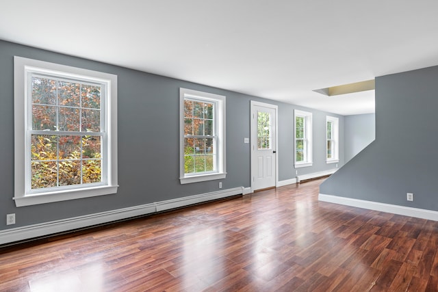 entrance foyer featuring a baseboard heating unit, plenty of natural light, and dark hardwood / wood-style flooring