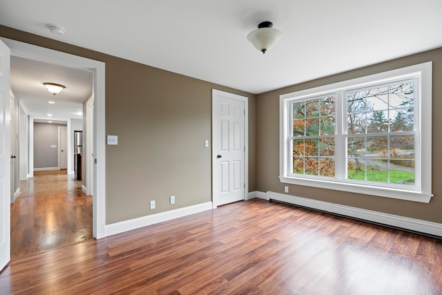 empty room with hardwood / wood-style floors and a baseboard radiator