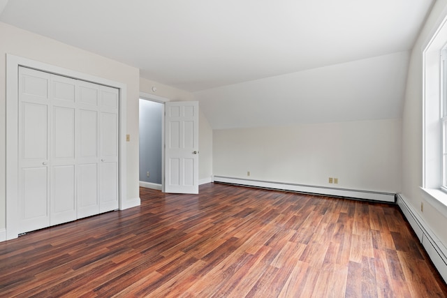 unfurnished bedroom with a closet, lofted ceiling, dark hardwood / wood-style floors, and a baseboard radiator