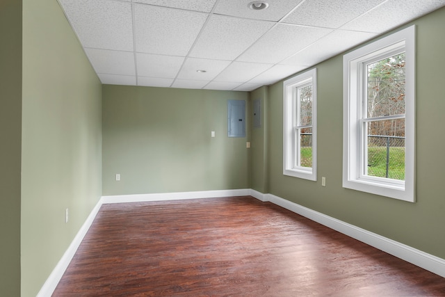 spare room featuring electric panel, a drop ceiling, and hardwood / wood-style flooring